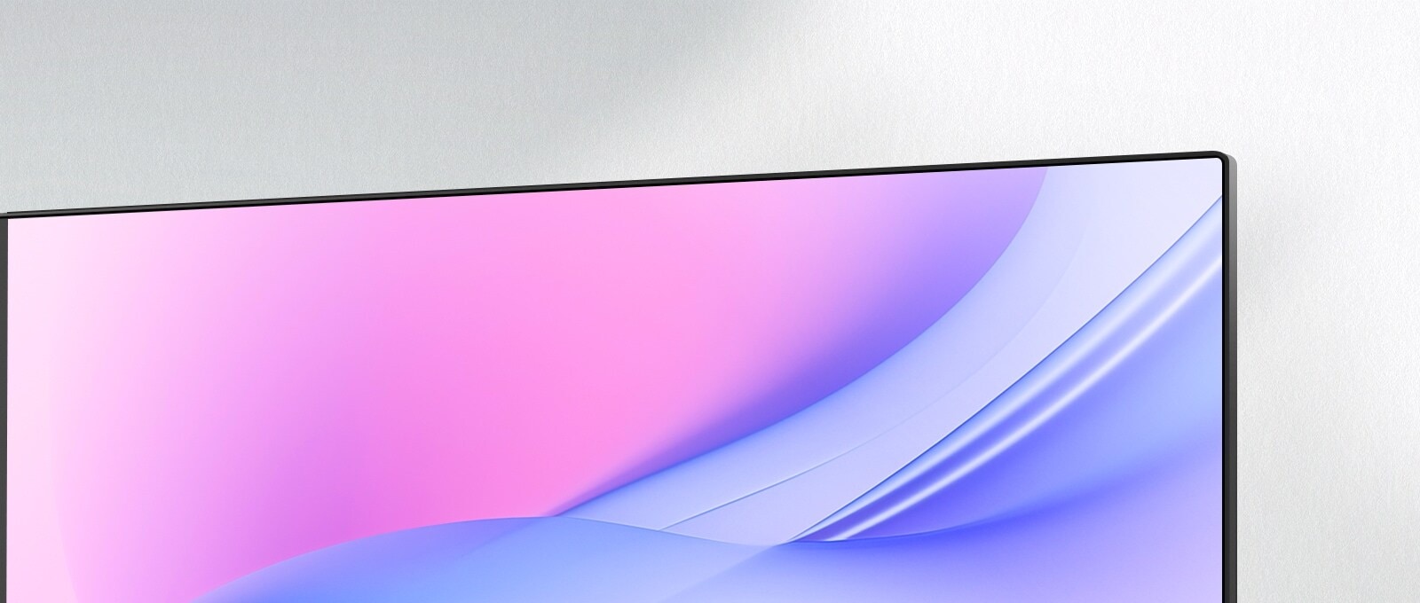 A close-up angled view of a monitor's upper-right corner, showcasing its ultra-slim bezel and seamless screen design. The display features a smooth pink-to-blue gradient, emphasizing a clean and modern aesthetic ideal for minimalistic setups.