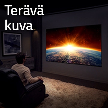 Pimeässä huoneessa sohvalla istuva mies katselee televisiota, joka näyttää nousevan auringon maan takana.