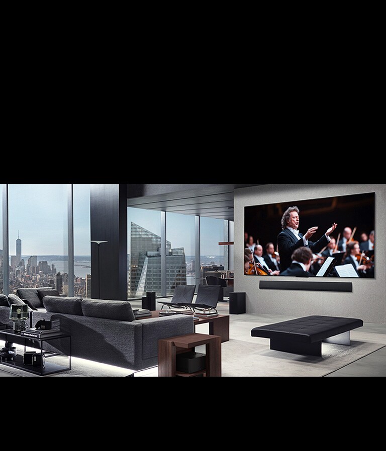 Olohuone, jossa on seinälle asennettu aidosti langaton LG-televisio ja LG Soundbar. Zero Connect Box tuskin näkyy sohvan vieressä olevan pöydän alta, mikä osoittaa, kuinka helppo se on asettaa minne tahansa. Koko olohuone näyttäytyy siistinä. 