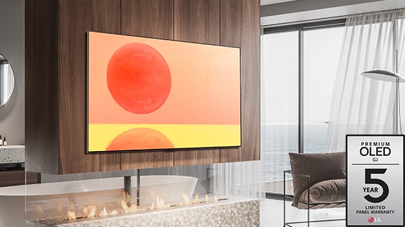 LG OLED G2 on ripustettu seinälle ruskeavalkoisessa huoneessa punaisten koristeiden kanssa G2:n viiden vuoden paneelitakuun logo