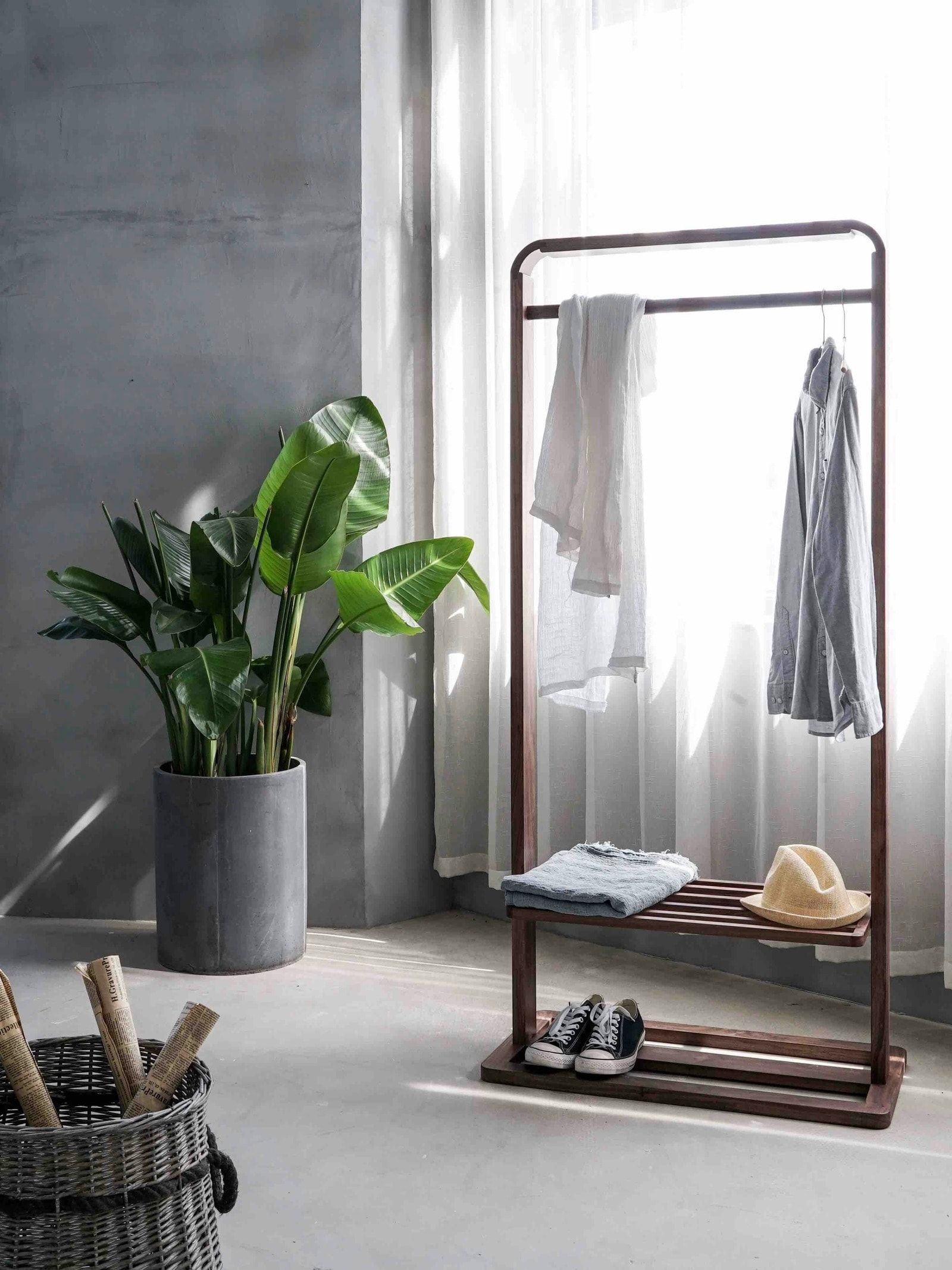 Une pièce moderne comprenant un portant avec plusieurs vêtements suspendus et un banc avec des vêtements pliés.