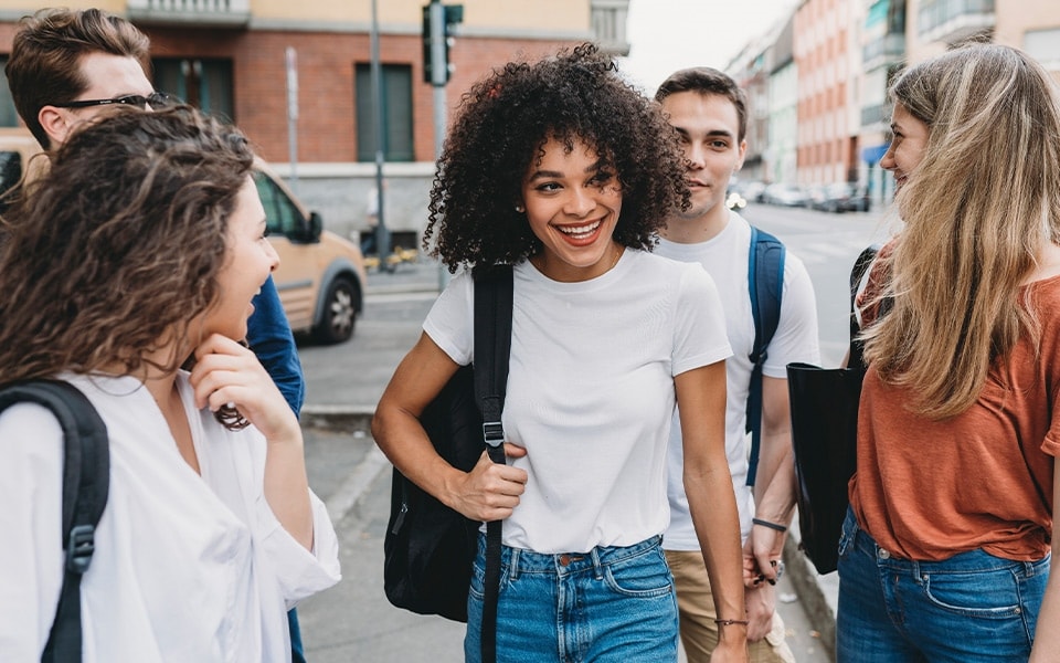 A happy young woman laughs while enjoying her smart good life with a group of friends.