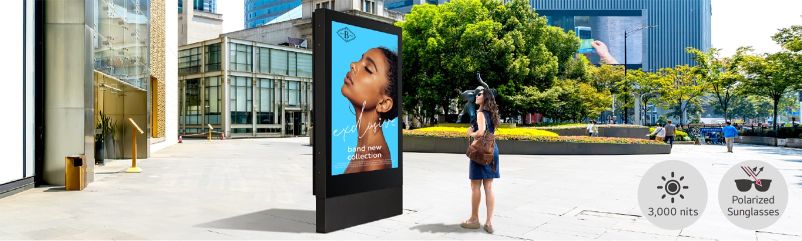 A large-sized display is installed on the street, and a woman is looking at a vivid-quality advertisement on the screen.