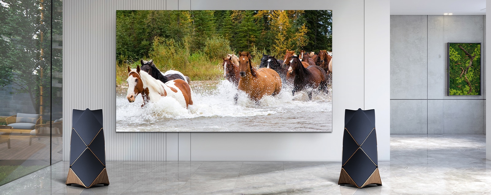 An LG MAGNIT installed on a living room wall, is vividly displays a herd of horses galloping through the water and dynamic sound coming from the Beolab 90 speakers located on both sides of the LG MAGNIT.