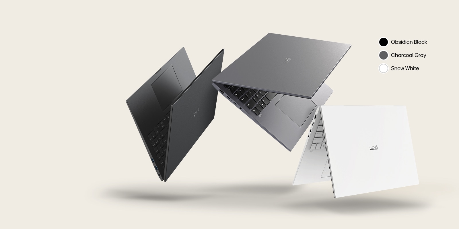 Three laptops in different colors: Obsidian Black, Charcoal gray, and Snow White, displayed in a dynamic arrangement against a beige background.