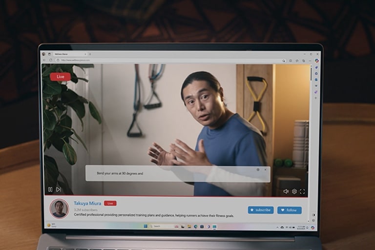 A live broadcast is displayed on the laptop screen, showing a man speaking. As he talks, subtitles with automatic translations appear at the bottom of the screen.	