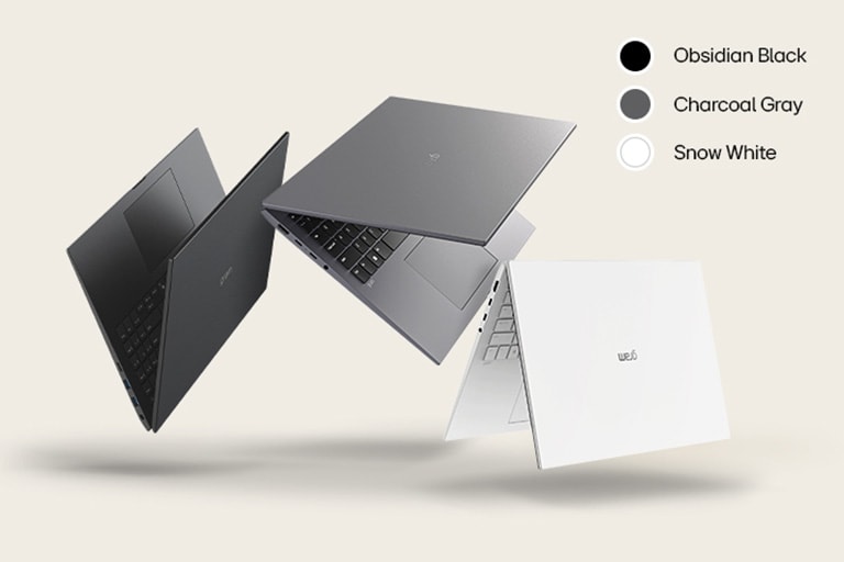 Three laptops in different colors: Obsidian Black, Charcoal gray, and Snow White, displayed in a dynamic arrangement against a beige background.	