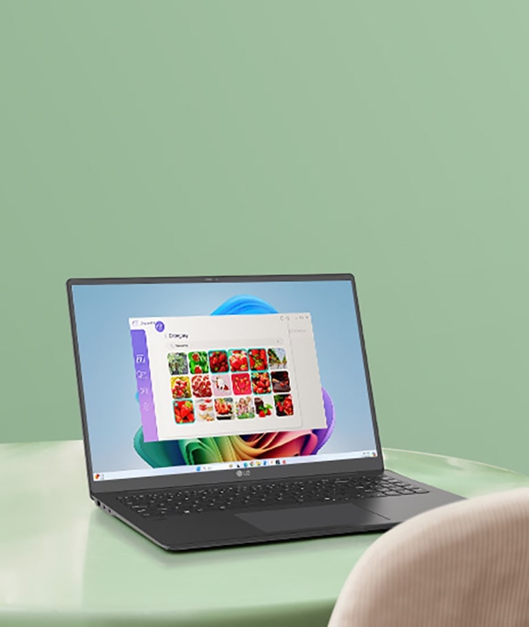 A laptop placed on a green table, displaying a gallery application interface with images of red fruits on the screen, suggesting navigation or photo management activities.	