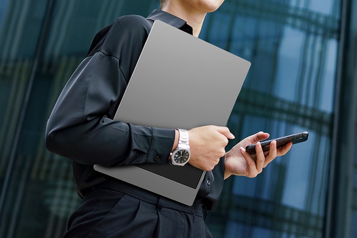 A woman is holding a phone in one hand and LG gram +view in the other.	