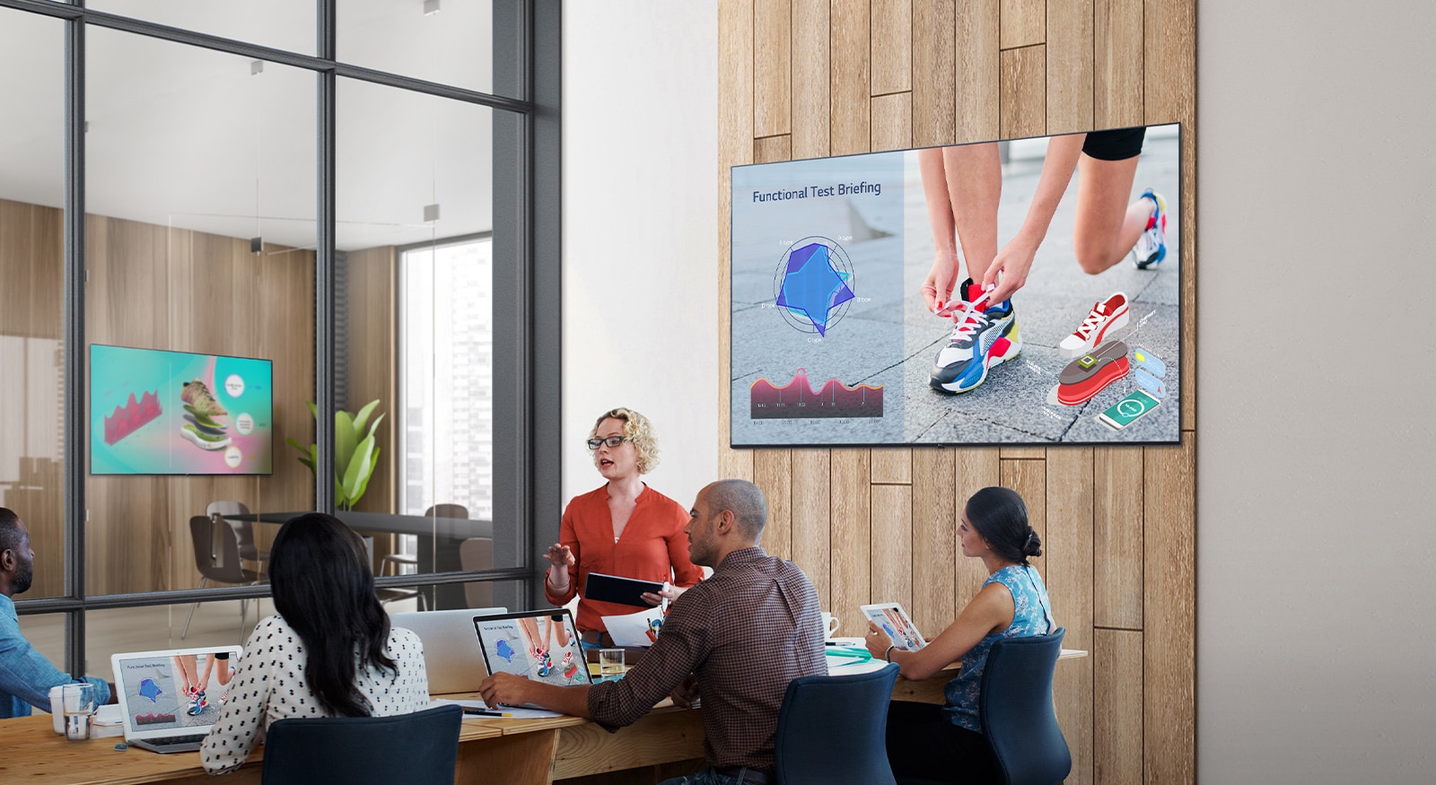 There are five people conducting a meeting in a room with UL3J series installed on the wall. There is another UL3J series installed across the meeting room on the wall past the window on the left.