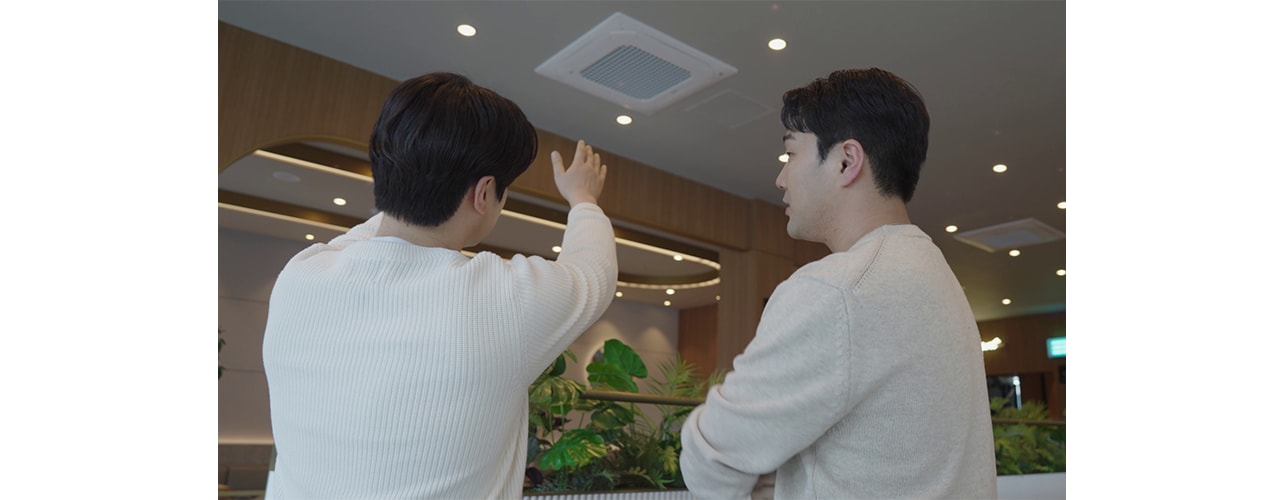Two men are talking while looking at the air conditioner.