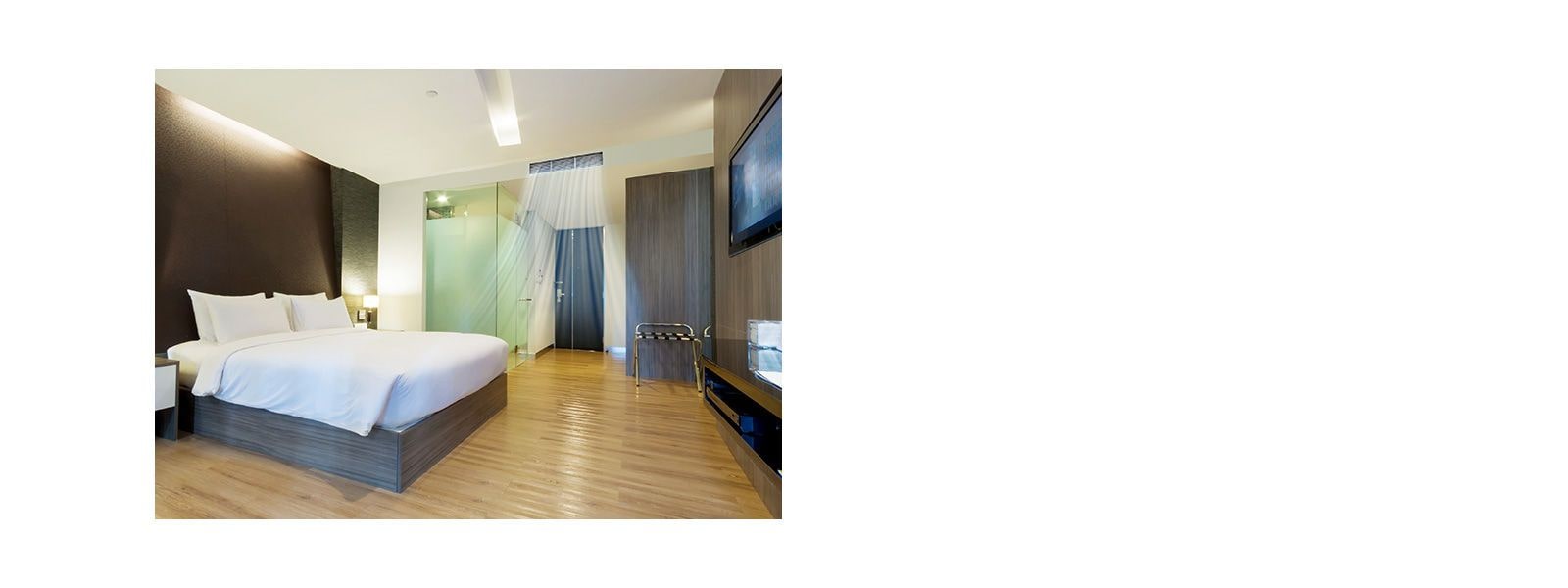 A ceiling concealed duct blows blue air in a hotel room with brown walls and a queen bed covered in white bedding.