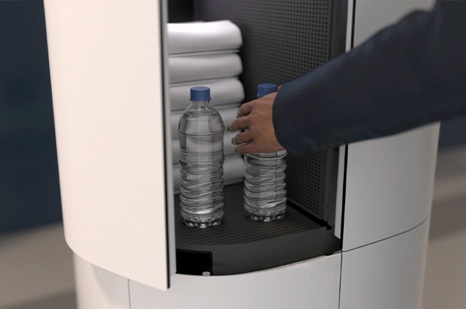 A man grabs the bottle of water in the storage of cloi servebot.	