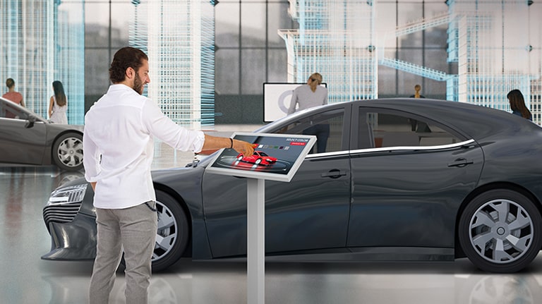 In a car dealership, a man is touching TNF3K to change the color of a car on the display.