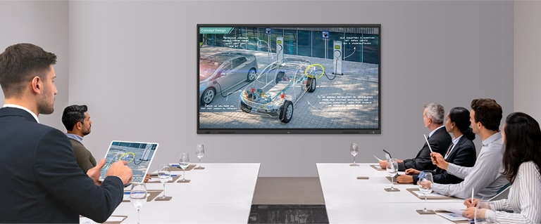 A presentation is underway in the meeting room equipped with an interactive smart board, with the presenter seamlessly controlling his materials via wireless screen sharing on his tablet.