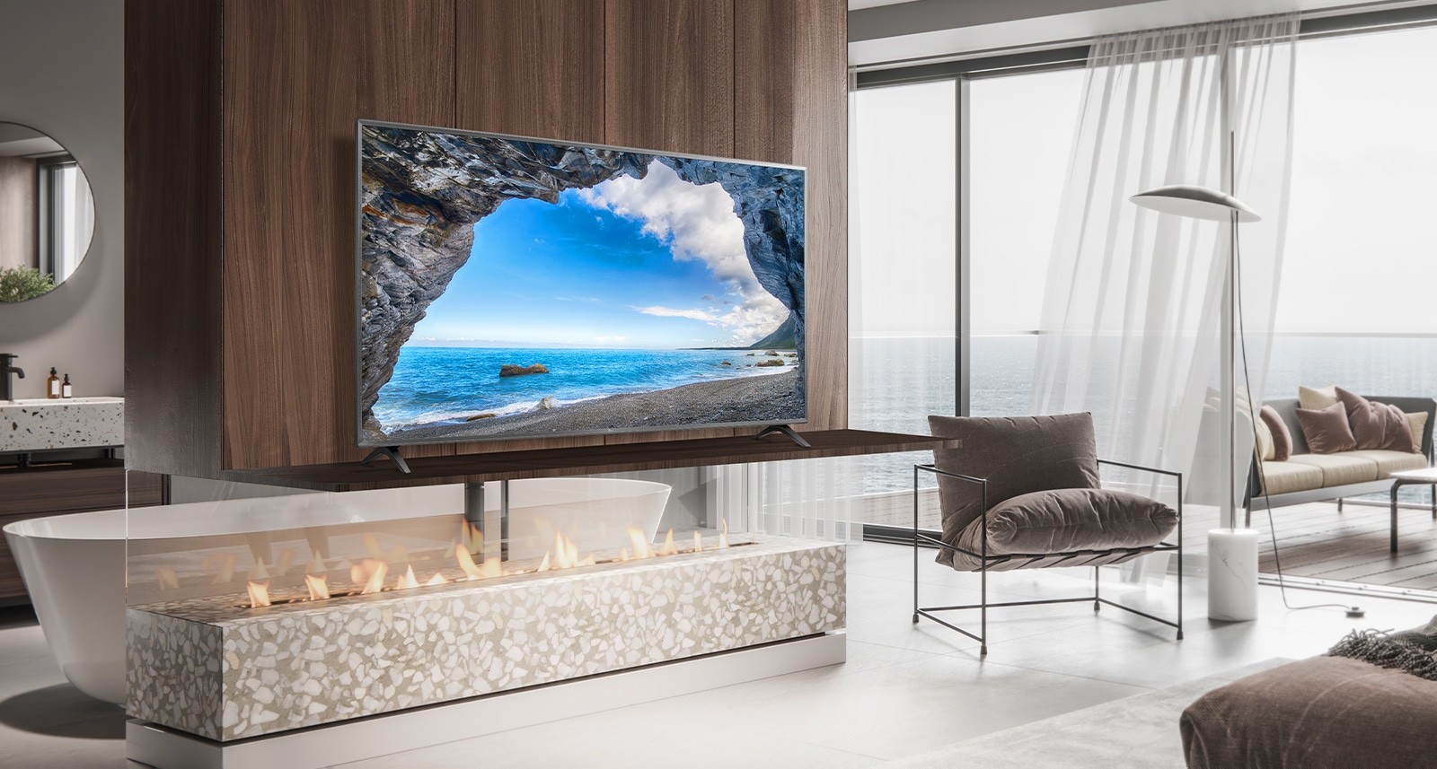 In a simple bedroom overlooking the sea, there is a TV on a wall shelf. The blue sea scenery appears bright and clear on the TV screen.