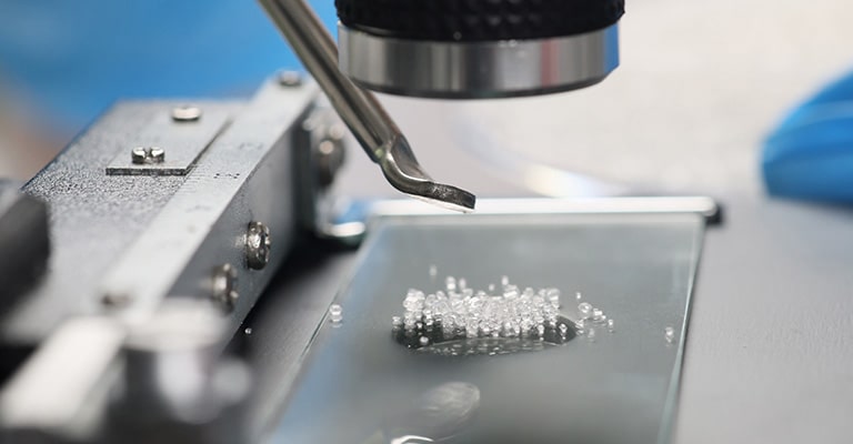 A zoomed-in tip of a microscope that is looking down on glass-like particles.