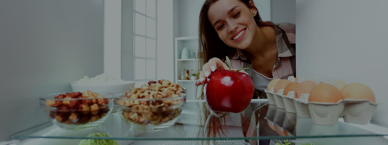 It's an image of a woman trying to get an apple out of the refrigerator.