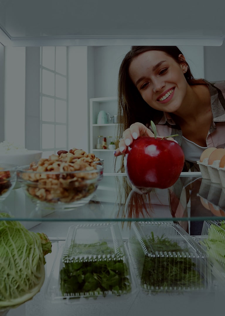 It's an image of a woman trying to get an apple out of the refrigerator.