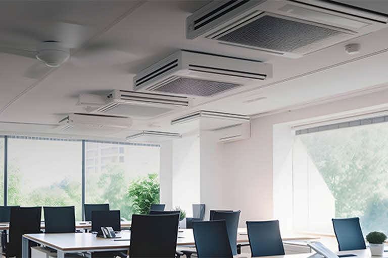 Bright office setting with multiple ceiling-type air conditioning units aligned in rows, delivering even and efficient airflow throughout a shared workspace.