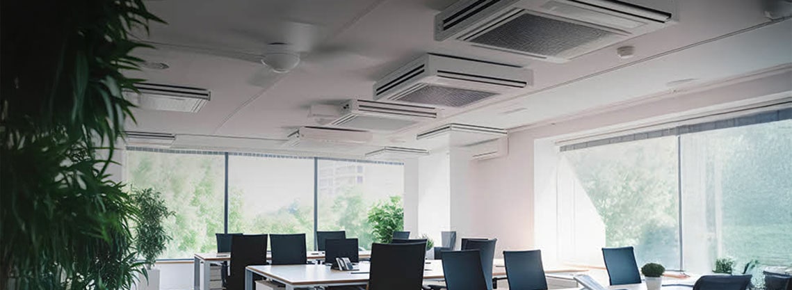 Bright office setting with multiple ceiling-type air conditioning units aligned in rows, delivering even and efficient airflow throughout a shared workspace.