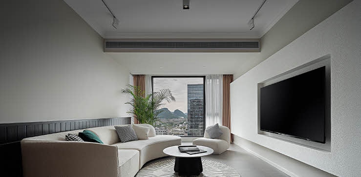 Modern living room interior featuring an duct-type air conditioner installed discreetly in the ceiling, providing invisible airflow for quiet residential or hospitality cooling.