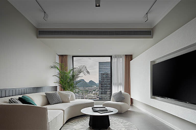 Modern living room interior featuring an duct-type air conditioner installed discreetly in the ceiling, providing invisible airflow for quiet residential or hospitality cooling.