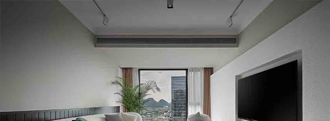 Modern living room interior featuring an duct-type air conditioner installed discreetly in the ceiling, providing invisible airflow for quiet residential or hospitality cooling.