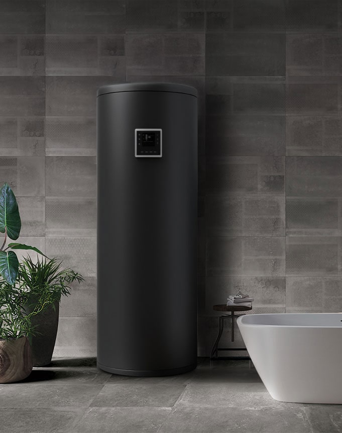 Matte black cylindrical Air to Water Heat Pump installed indoors against a tiled wall, next to a modern white bathtub.