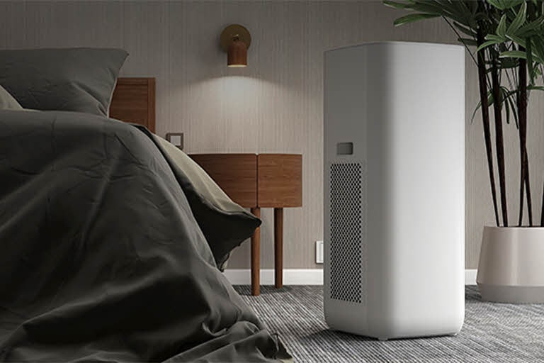 Cozy bedroom with an LG dehumidifier placed beside a bed, showcasing sleek design and moisture control functionality in a comfortable residential environment.