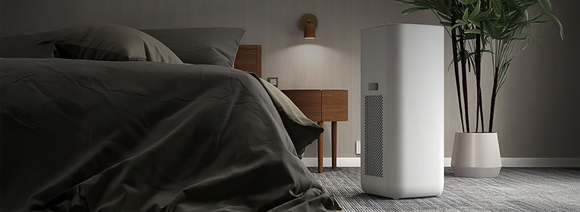 Cozy bedroom with an LG dehumidifier placed beside a bed, showcasing sleek design and moisture control functionality in a comfortable residential environment.
