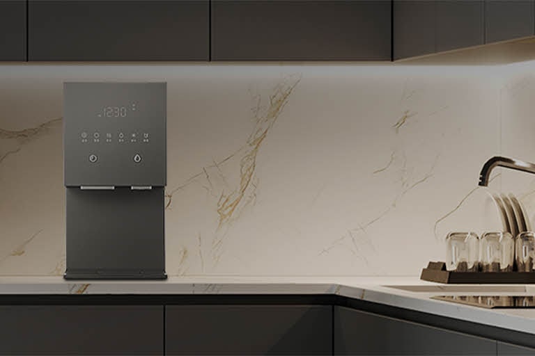 Minimalist kitchen counter with an hot and cold water purifier placed against a marble backsplash, delivering purified water with precise temperature control.