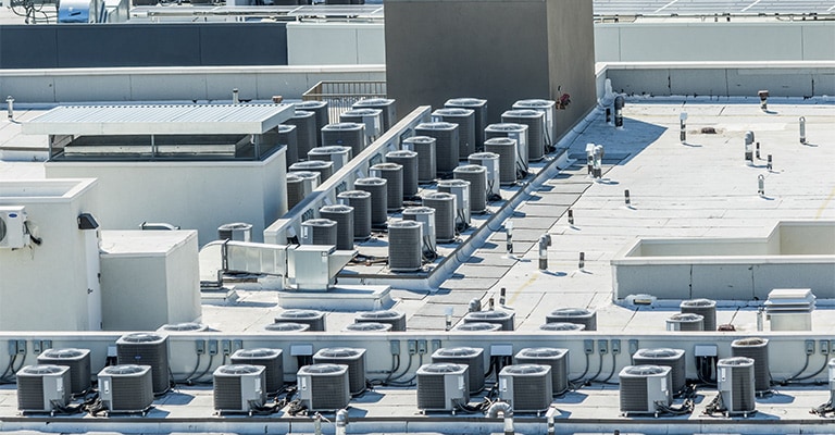 An overhead view of a densely packed commercial rooftop, dominated by numerous HVAC units. 