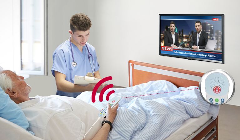 A patient lying in the bed is watching TV while listening to it through a pillow speaker.