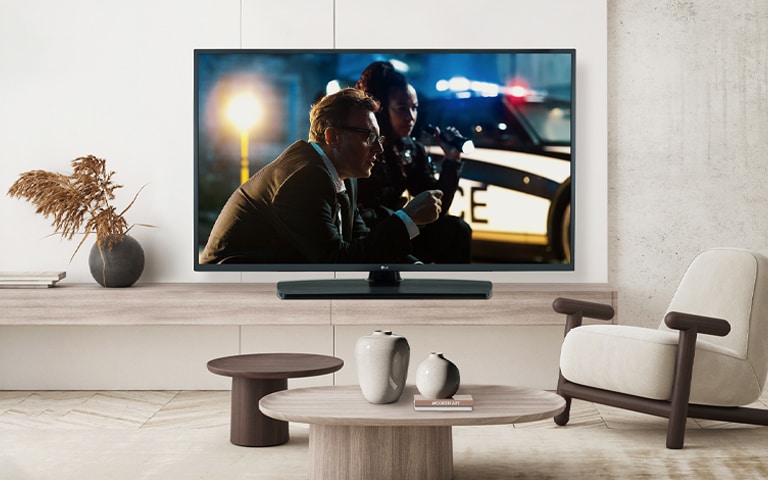 A TV by a hotel’s wall shows a bright and vivid screen.