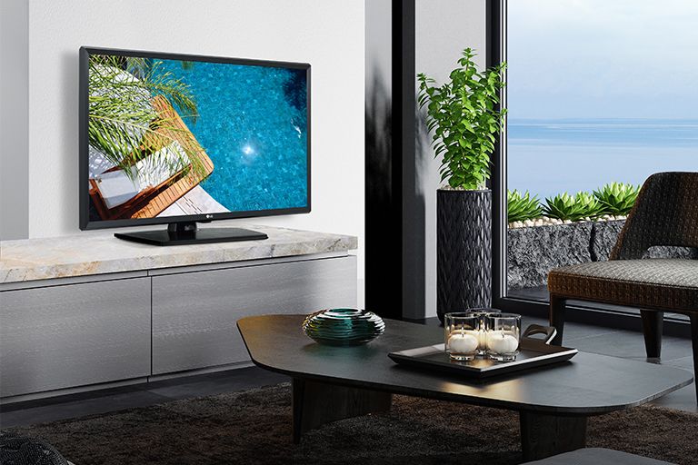 A TV is placed on the wall of the hotel room, and the screen displays a clear view of the hotel swimming pool scenery.