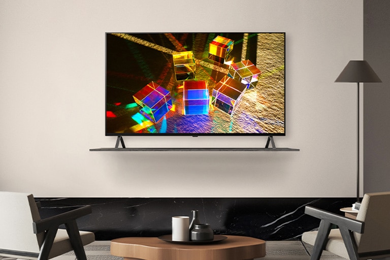 A TV is placed on a shelf on a hotel wall, and the screen vividly displays an image of objects reflecting colorful light.