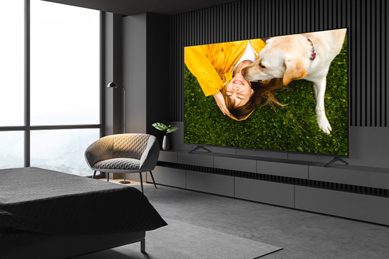 A TV is installed on a stand close to the wall in the hotel room, and the screen is bright and clear.