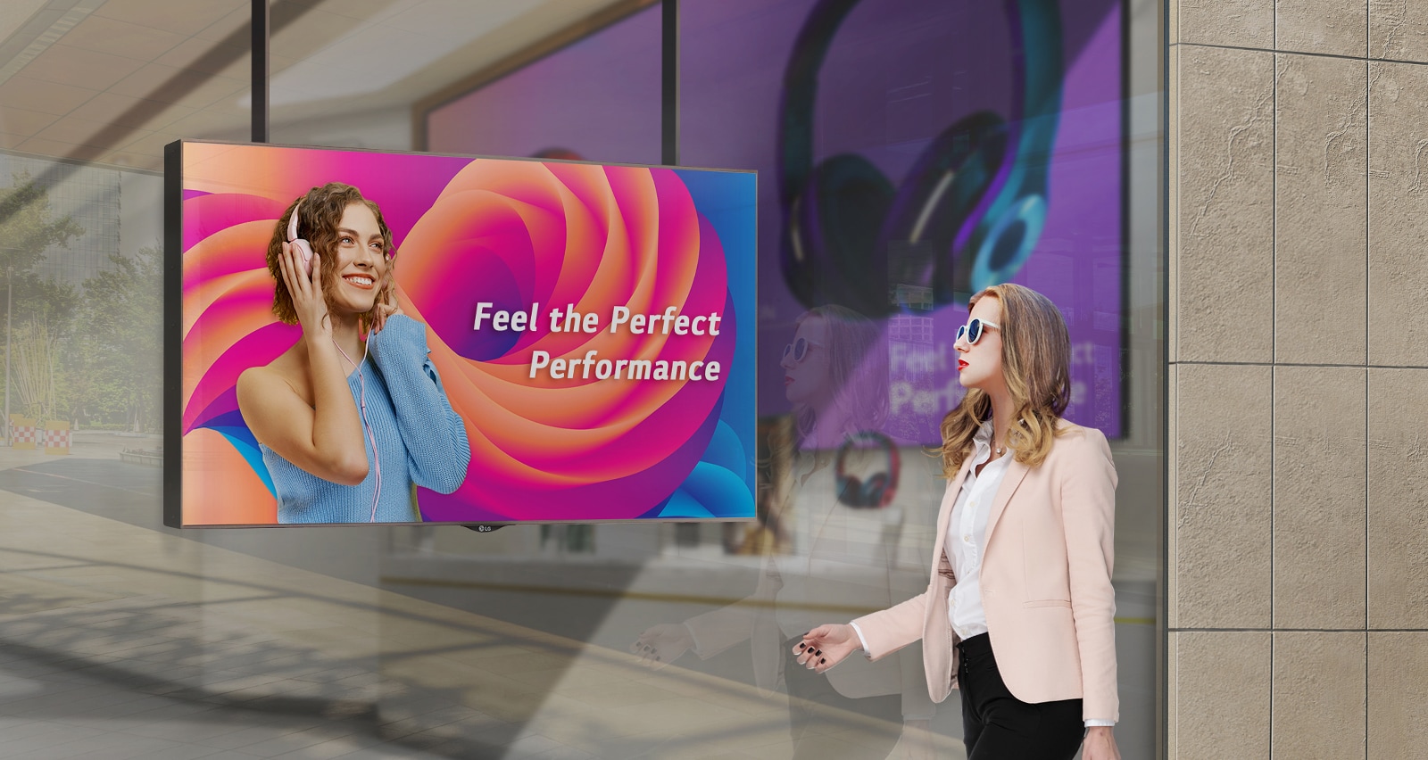 A woman wearing sunglasses is watching ads on the display installed in a shop window, and the ads on the display are very visible even under the strong sunlight.