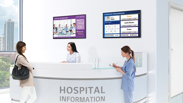 Two TVs are installed on the hospital information desk’s wall, and each screen is displaying the hospital and doctors’ information.