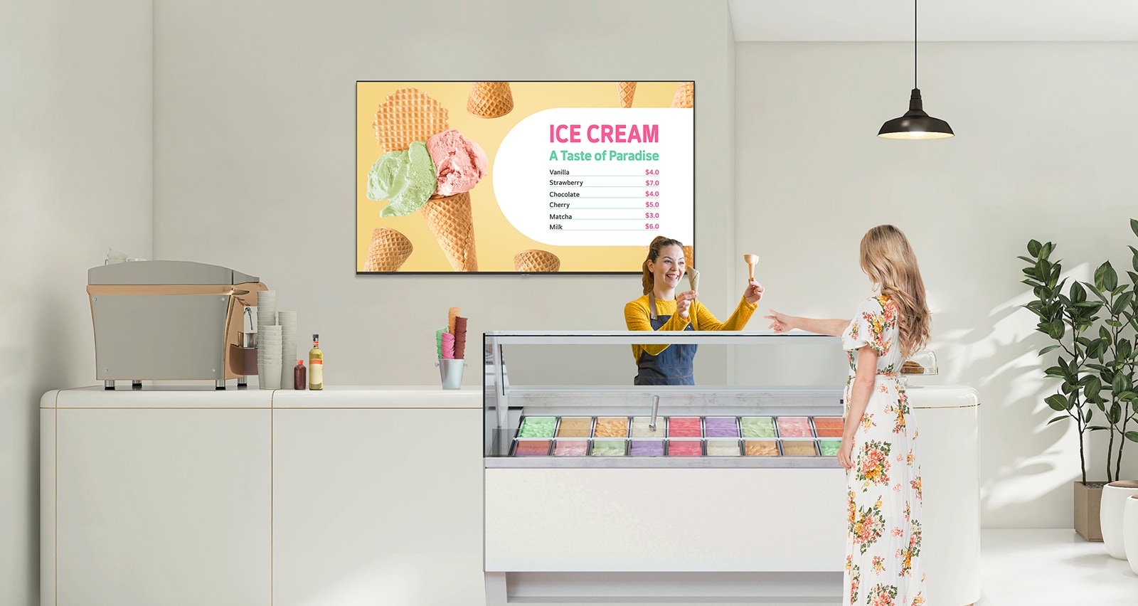 In an ice cream shop, a UM340E is installed on the wall. The screen of the UM340E displays the menu prominently, and the customer is choosing her ice cream.