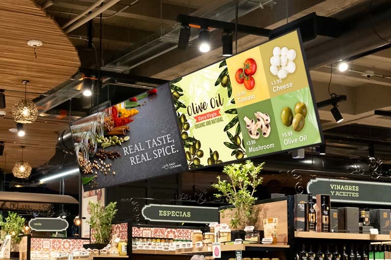 Two UP5Q-E displays are installed side by side in the mart. The left screen displays advertisements in full screen, while the right one shows ads in a split-screen layout.