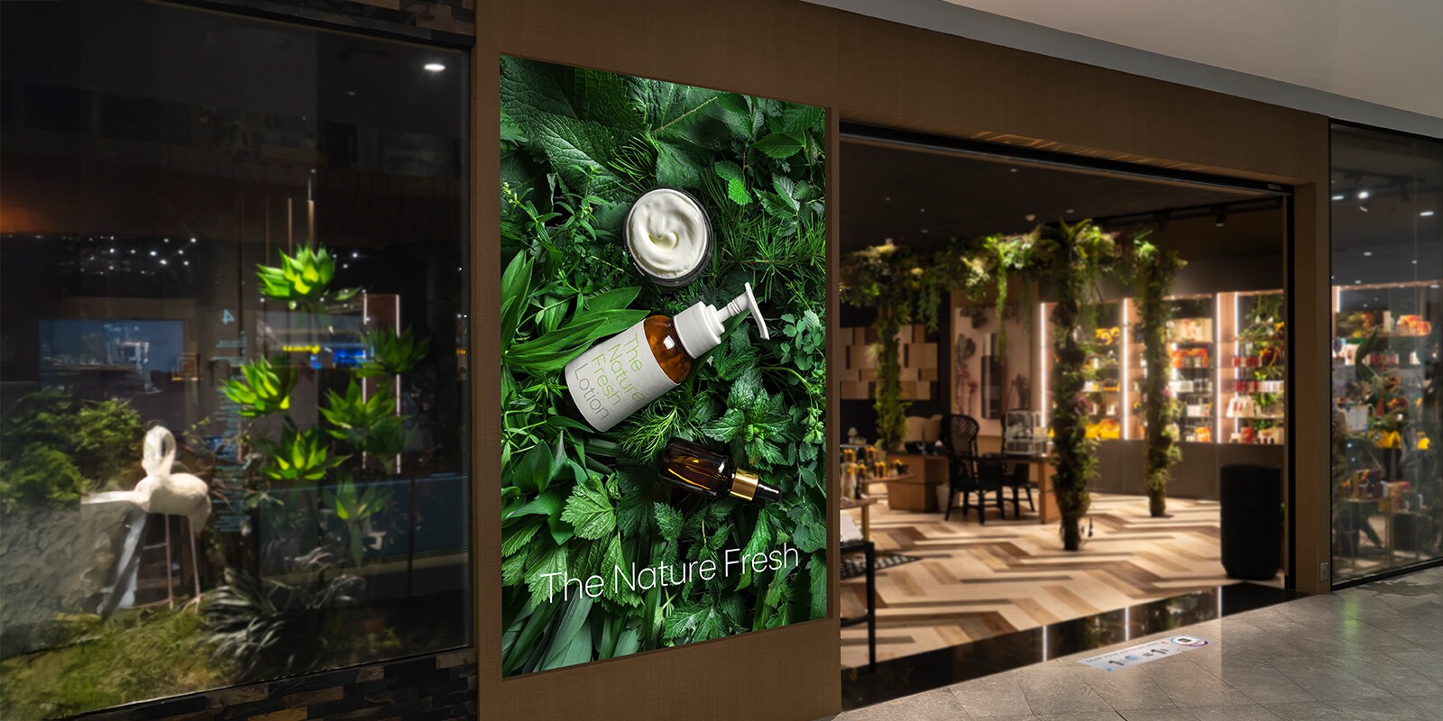 A large LED display is integrated with the wall next to a store entrance in a shopping mall, clearly displaying an advertisement.