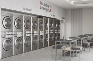 LG Laundry Lounge is shown from a side view, featuring LG Commercial Laundry machines installed in a stacked configuration, with desks and chairs arranged in the space.