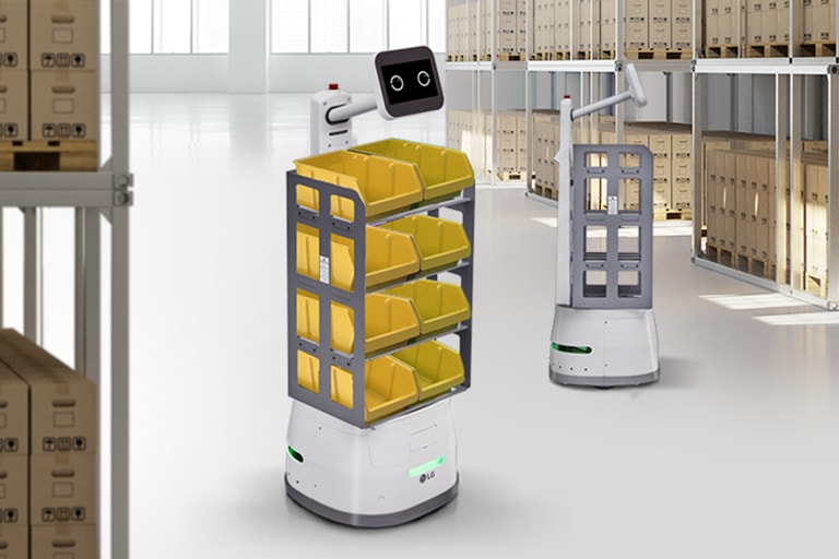 Two CarryBots are in a container space one closer to the frame carrying two tote boxes on each tray.	