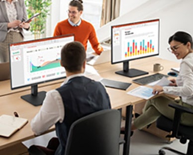 Employees sitting at office desks and having a conversation. 