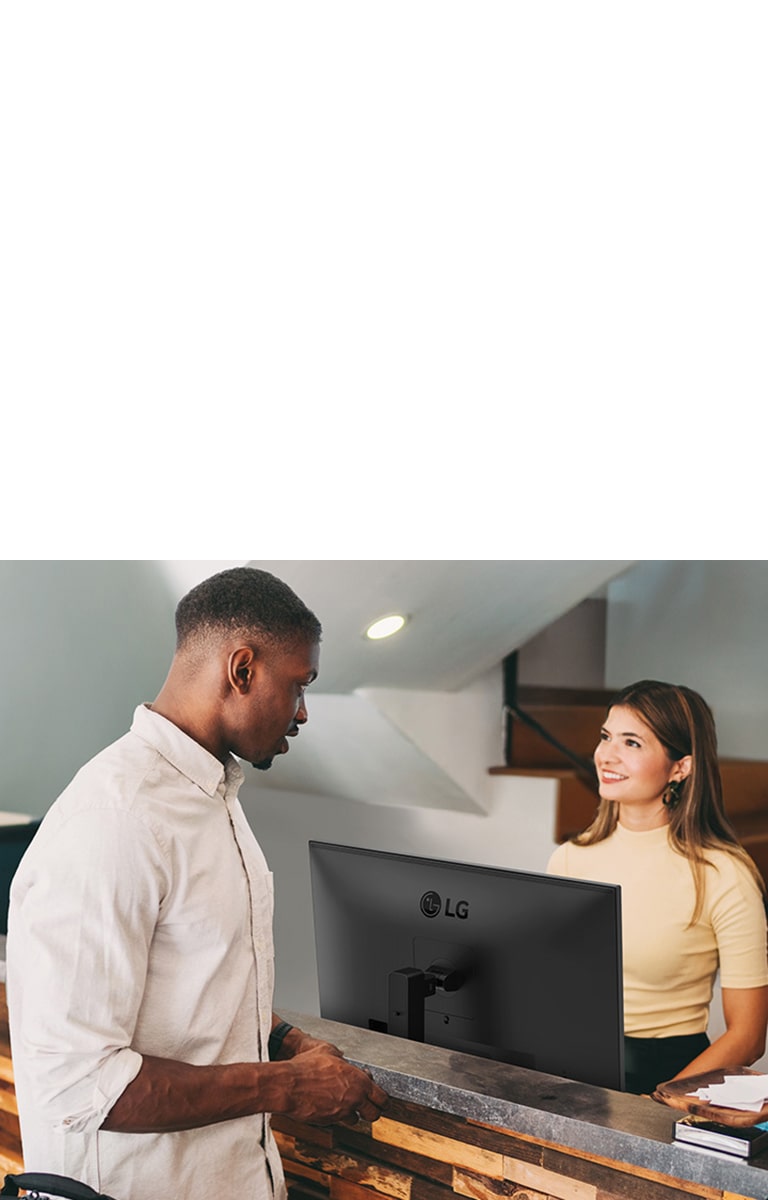 A female receptionist is talking to a man at the front desk.	