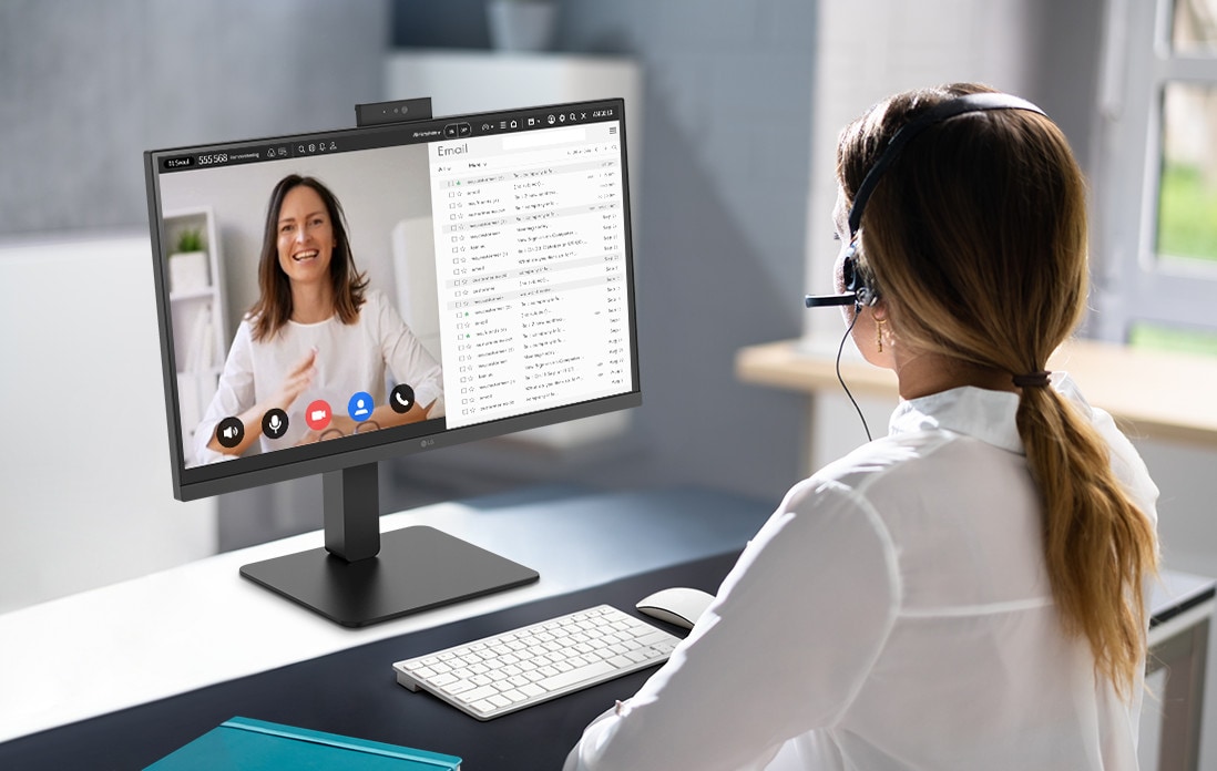 A woman wearing a headset is video conferencing with the built-in webcam. 