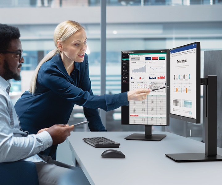 Two male and female employees discuss while looking at the monitor in the office.	