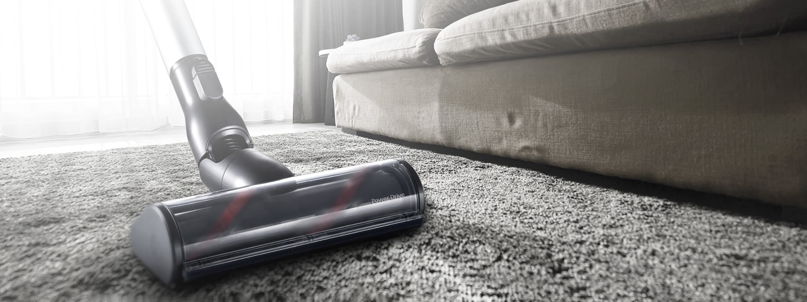 He's pushing a vacuum in the living room.